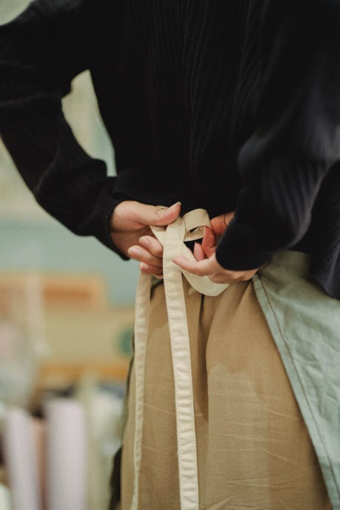 crop faceless woman tying up apron laces